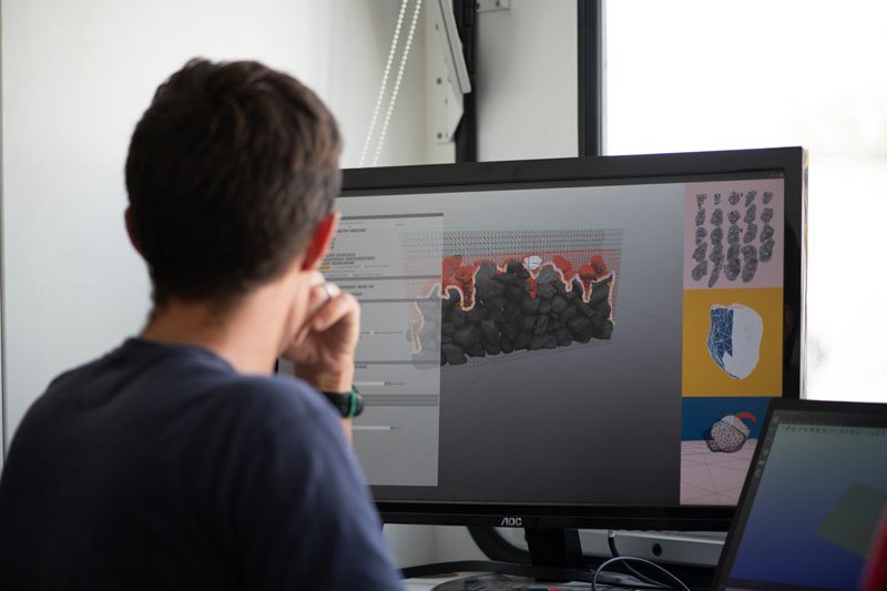 researcher looks at computer with image of 3d model of wall