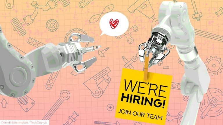 Two industrial robot arms, one holding a sign that says "We're hiring, join our team"