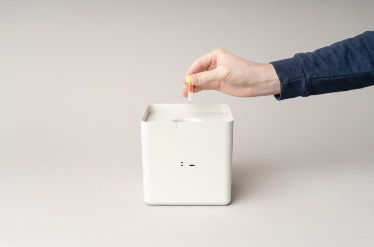 A person putting a vial in a battery-powered cold shipping container.