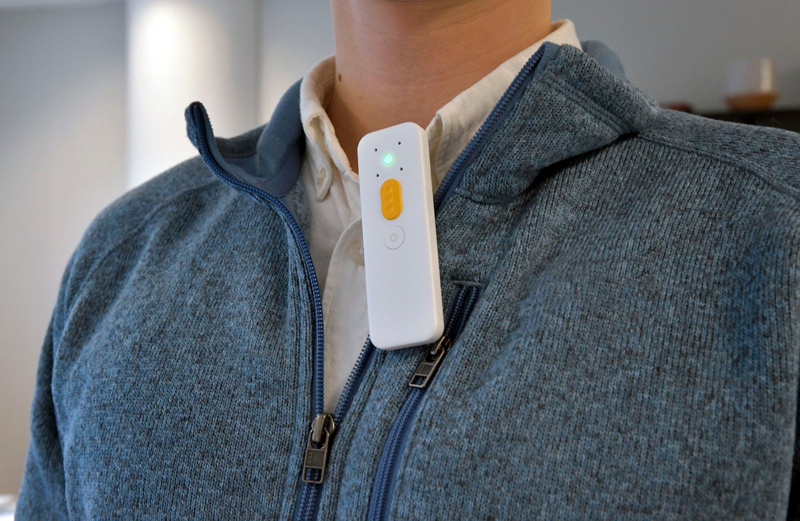 an image of the speaksee microphone clipped to the collar of a person wearing a blue sweater