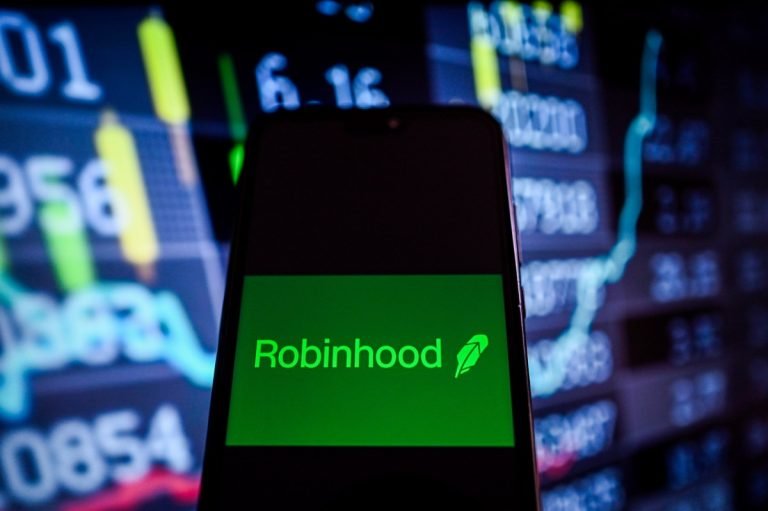 This photo illustration shows a Robinhood logo is displayed on a smartphone with stock market percentages on the background.
